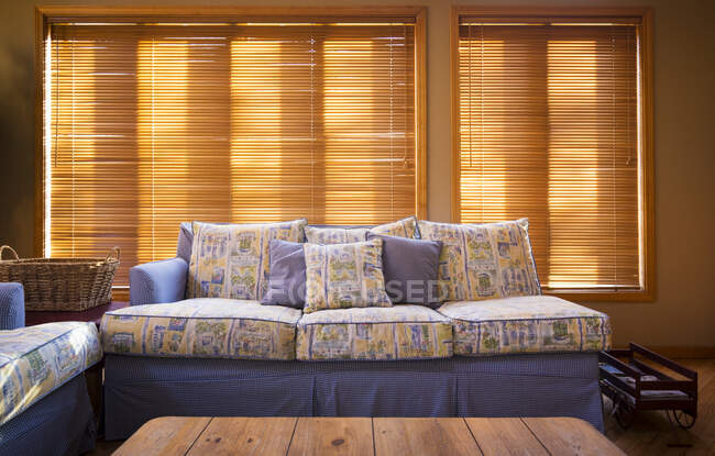 Holzjalousien hinter Sofa im Wohnzimmer — Stockfoto