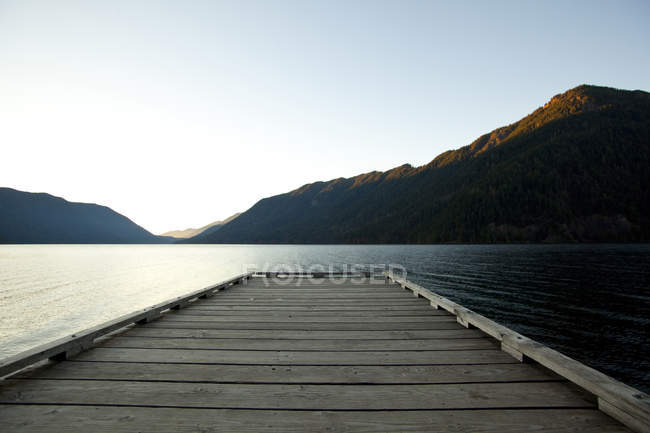 Деревянная палуба у озера под голубым небом — стоковое фото