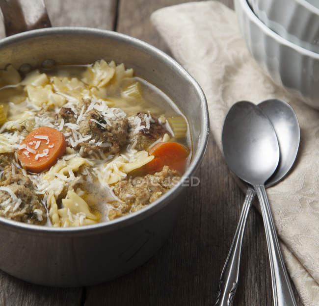 Primer plano del tazón de sopa de pasta con cucharas en la mesa - foto de stock