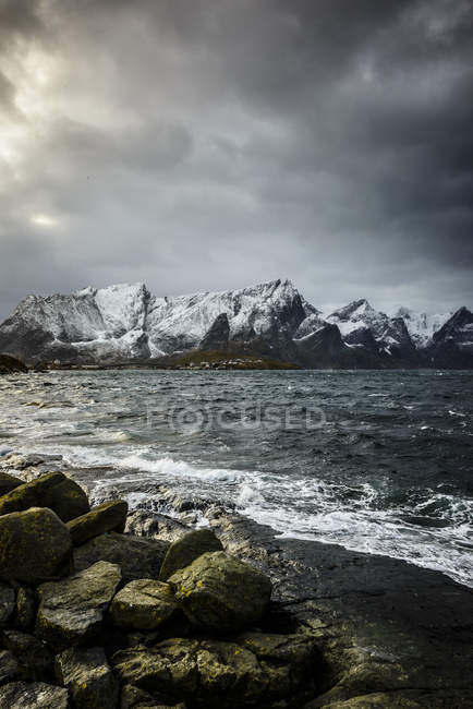 Montañas nevadas con vistas a la costa rocosa, Reine, Islas Lofoten, Noruega - foto de stock
