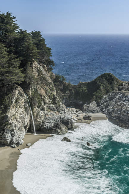Водоспад наливається в хвилях миття на скелястому пляжі, Юлія Пфайфер Бернс State Park, Каліфорнія, США — стокове фото