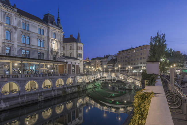 Будинки і пішохідний міст над міським каналом у вечірній час, Любляна, Центральна Словенія, Словенія — стокове фото