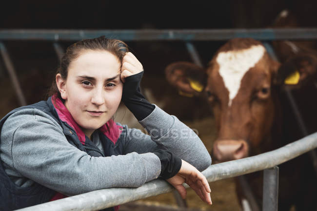 Retrato de una joven de pie junto a la vaca Guernsey en la granja . — Stock Photo