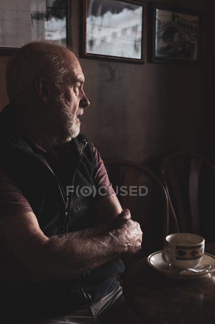 Бородатий чоловік, сидячи за столом з чашкою кави в місцевому кафе, Венеція, Італія — стокове фото