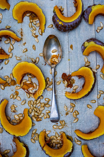 Close-up of silver tablespoon and slices of pumpkin on blue background. — Stock Photo