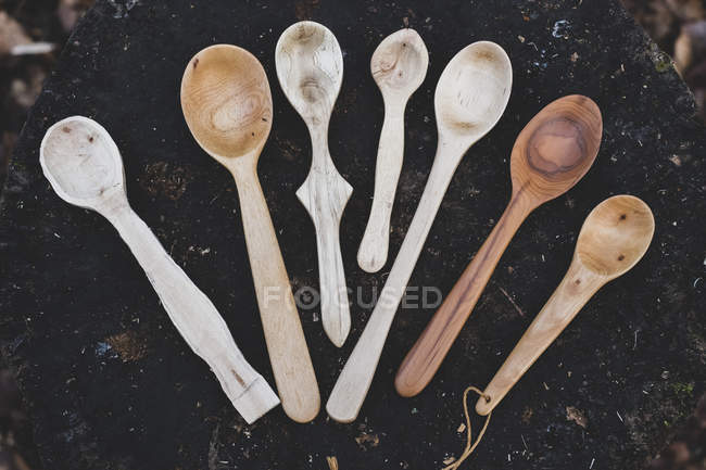 Close-up of selection of carved wooden spoons on chopping block. — Stock Photo