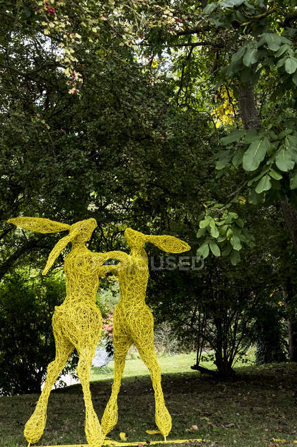 Boxe lièvres sculpture de jardin peinte en jaune dans l'Oxfordshire, Angleterre — Photo de stock