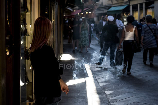 Mujer local parada en una calle estrecha en Venecia, Véneto, Italia y fumando un cigarrillo . - foto de stock