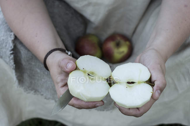Close-up de mãos femininas segurando maçãs cortadas ao meio . — Fotografia de Stock