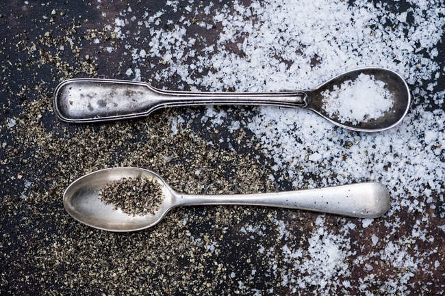 Dos cucharas pequeñas con cristales de sal en la mesa grunge . - foto de stock