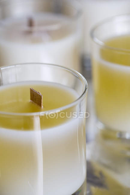 High angle close-up of handmade white and yellow jar candles with wooden wick. — Stock Photo