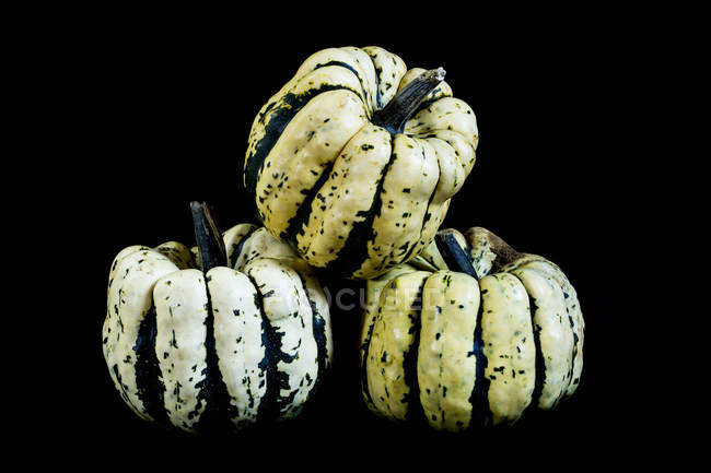 Close-up of three sweet dumpling squashes on black background. — Stock Photo
