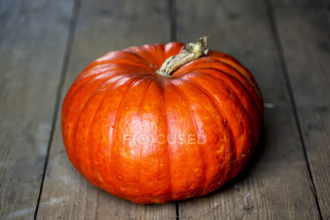 Close-up of bright orange pumpkin on rustic wooden table. — Stock Photo