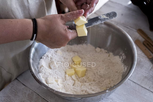Hohe Nahaufnahme einer Person, die Butter und Mehl zum Zerbröseln in einer Metallschüssel mischt. — Stockfoto