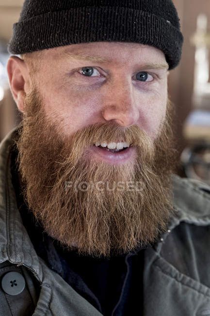Retrato de homem barbudo sorridente com cabelo castanho, vestindo gorro preto . — Fotografia de Stock