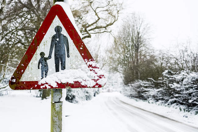 Nahaufnahme von Fußgängern in Verkehrszeichen auf schneebedeckter Landstraße. — Stockfoto