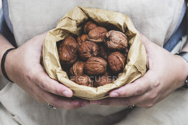 Крупним планом людина тримає коричневий паперовий мішок зі свіжими волоськими горіхами . — стокове фото