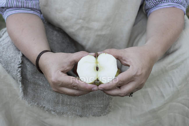 Nahaufnahme einer Frau, die einen halbierten Apfel hält. — Stockfoto