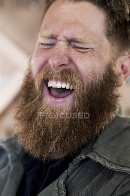 Portrait of laughing bearded man with brown hair. — Stock Photo