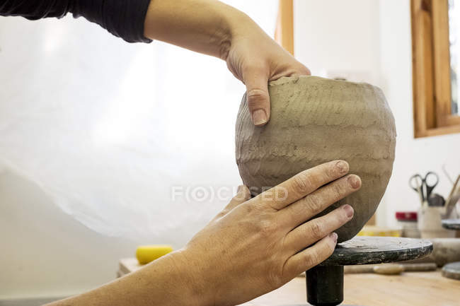 Nahaufnahme eines Keramikkünstlers in einer Werkstatt, der an einer kleinen Tonvase arbeitet. — Stockfoto
