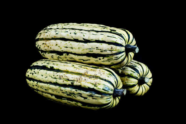 Close-up of three Delicata squashes on black background. — Stock Photo