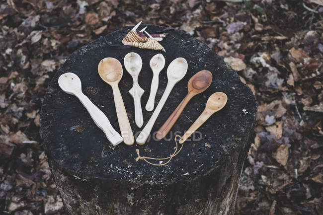 High angle close-up of selection of carved wooden spoons on chopping block. — Stock Photo