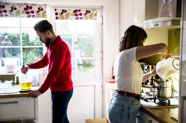 Homem e mulher em pé na cozinha doméstica e fazendo velas jar . — Fotografia de Stock