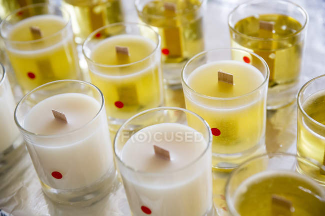 Alto ângulo close-up de velas de jarra brancas e amarelas artesanais com pintos de madeira . — Fotografia de Stock