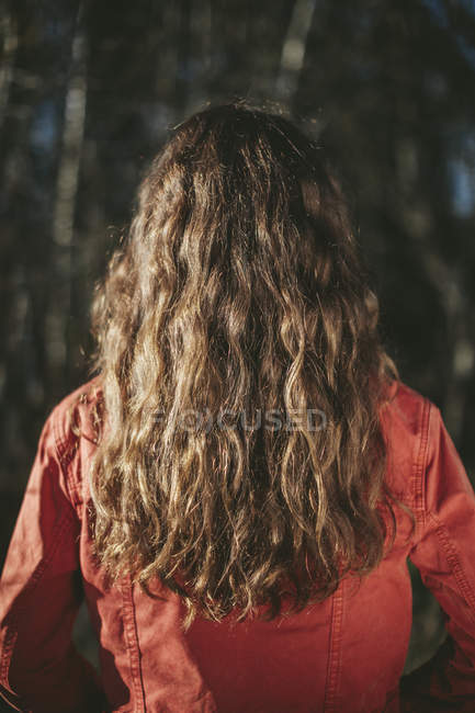 Vista posteriore di ragazza adolescente con lunghi capelli castani ondulati in piedi all'aperto — Foto stock