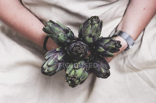 Midsection of person holding bunch of fresh artichokes. — Stock Photo