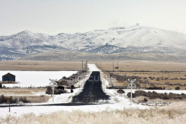 Attraversamento ferroviario innevato con montagne nello Utah, USA — Foto stock