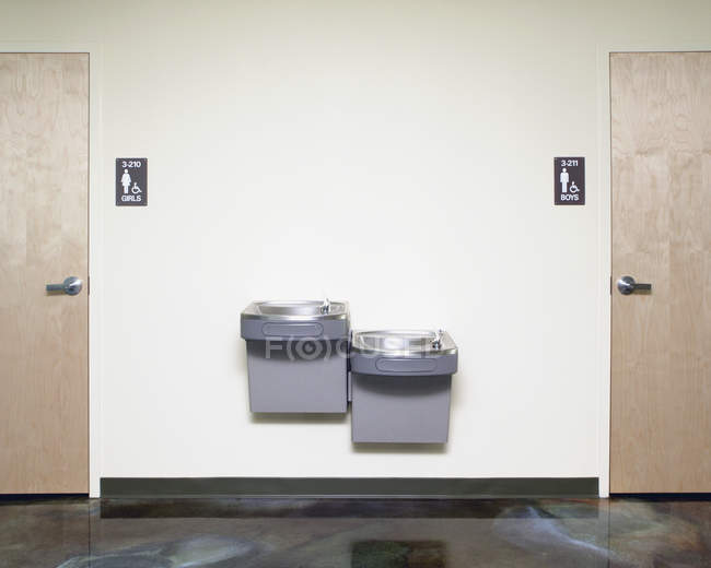 Fontaines à boire près des toilettes mâles et femelles portes — Photo de stock