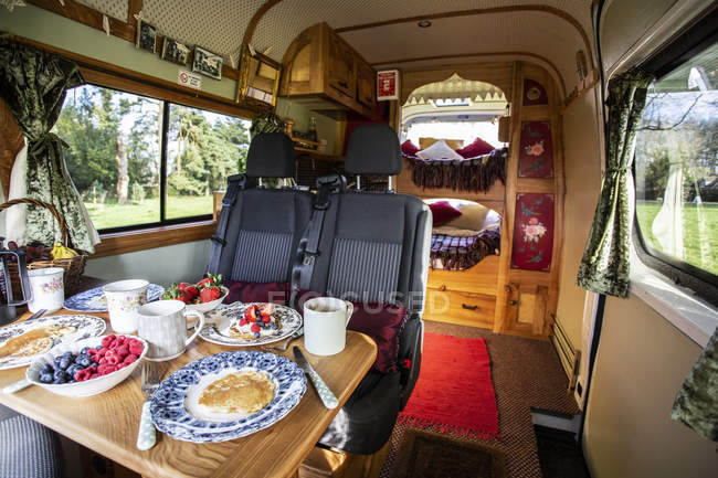 Vista interior de autocaravana con comida de desayuno en la mesa . - foto de stock