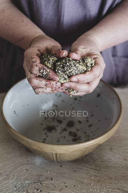 Mains de la personne pétrissant la pâte sur le bol de mélange . — Photo de stock