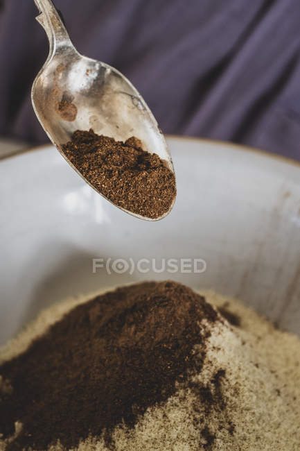 Close-up de derramamento de cacau em pó de colher em tigela de mistura com ingredientes de cozimento . — Fotografia de Stock