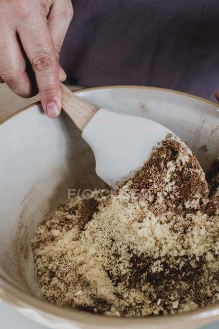 Primer plano de la persona mezclando la masa a mano ingredientes para hornear utilizando espátula . - foto de stock