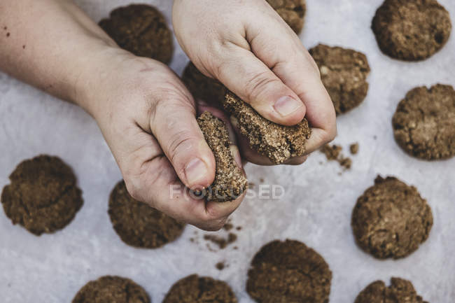 Nahaufnahme einer Person, die frisch gebackene Schokoladenkekse halbiert. — Stockfoto