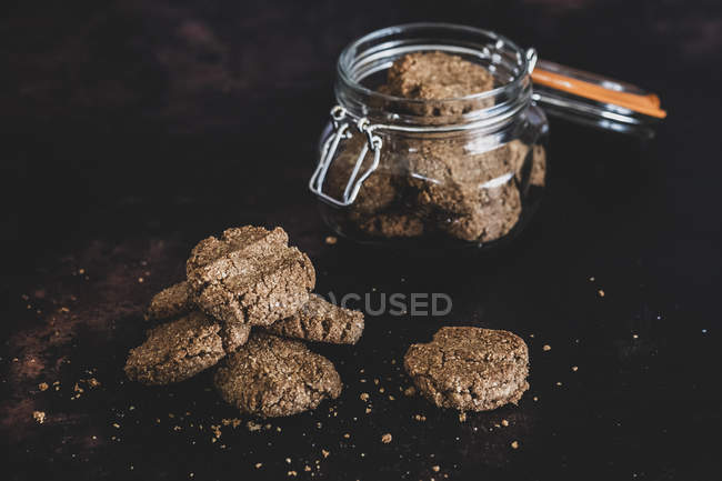 Gros plan sur grand angle des biscuits au chocolat fraîchement cuits dans un bocal en verre et une surface noire . — Photo de stock