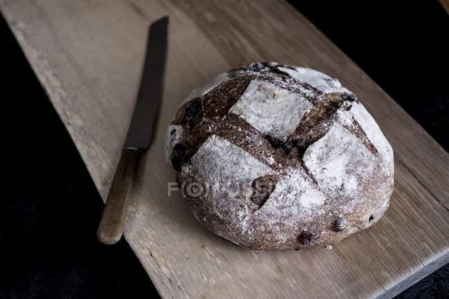 Blick von oben auf Laib frisch gebackenes braunes Brot mit dicker Kruste auf Holzbrett. — Stockfoto