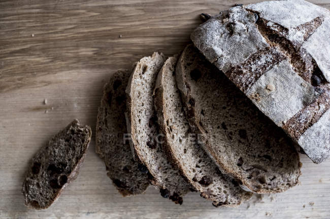 Hochwinkelblick auf geschnittene Laibe frisches braunes Brot auf Holzbrett — Stockfoto