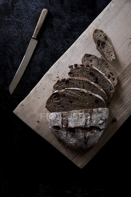 Hochwinkelblick auf Laibe frisches braunes Brot an Bord mit scharfem Messer — Stockfoto