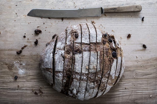 Высокий угол обзора буханки свежего нарезанного коричневого хлеба на борту с ножом — стоковое фото
