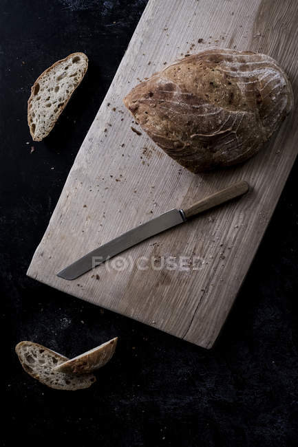 Vista de alto ângulo de pão marrom a bordo com faca de pão — Fotografia de Stock