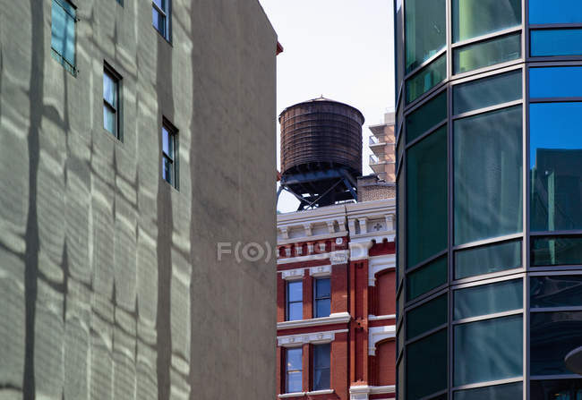 City water tower seen behind buildings in New York City, New York, USA — Stock Photo