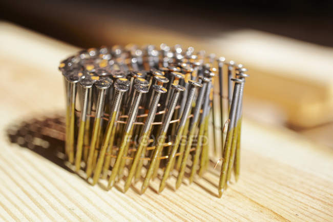 Clavos de encuadre en espiral en superficie de madera, primer plano - foto de stock