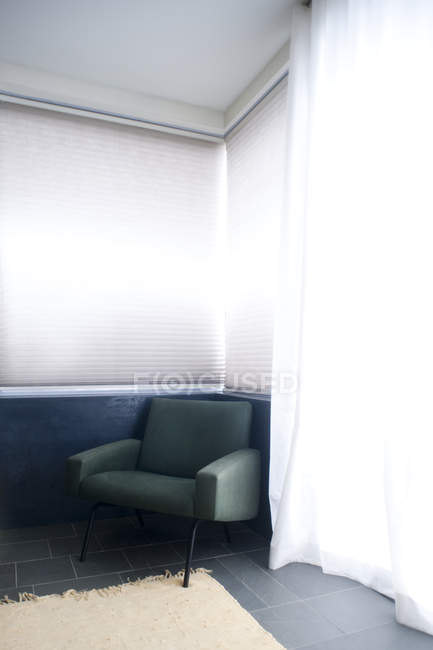 Silla en habitación de color claro con alfombra y cortina - foto de stock