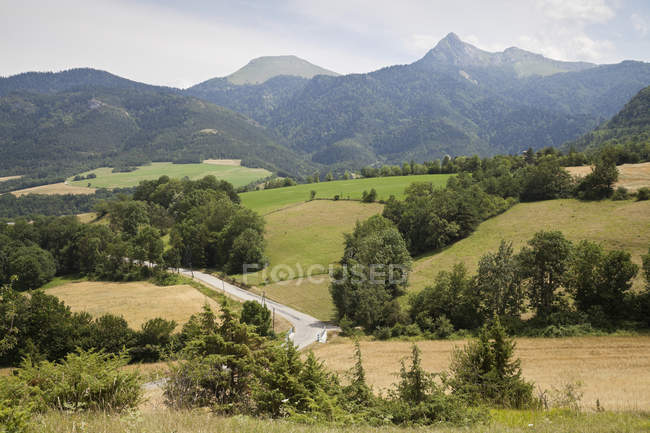 Tal mit Feldern und Bauernhöfen und Bergen in der Ferne, Frankreich — Stockfoto