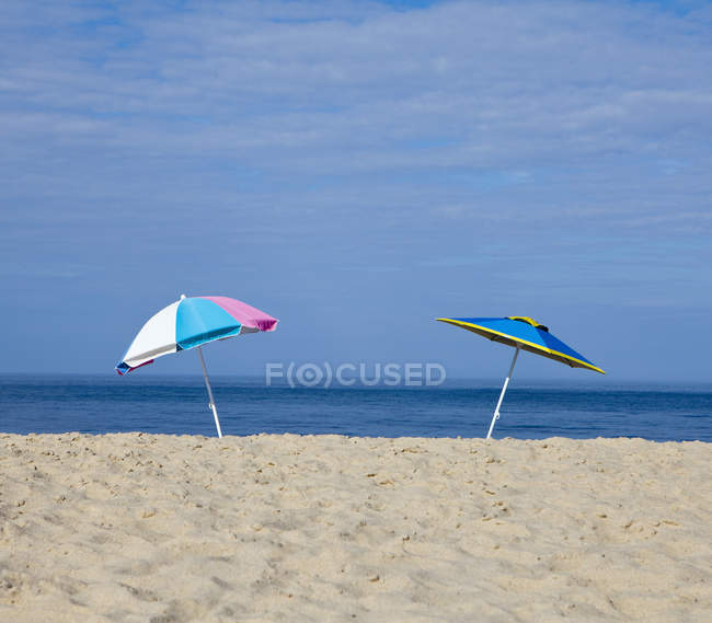 Parapluies de plage en sable avec paysage marin bleu — Photo de stock