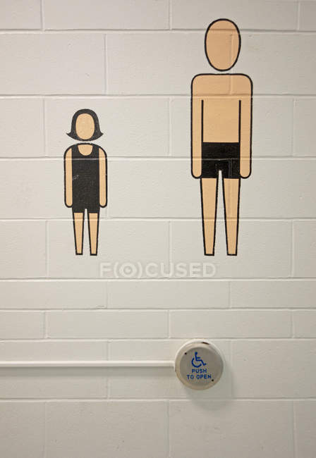 Accessibility door press and silhouettes on wall at public swimming pool — Stock Photo