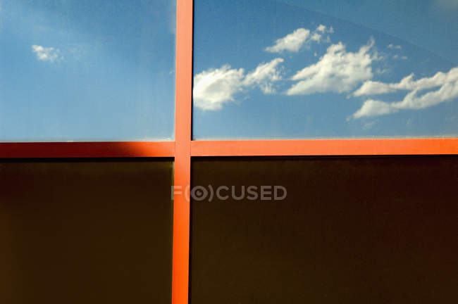 Облака, отражающиеся в стеклянном фасаде с окном — стоковое фото